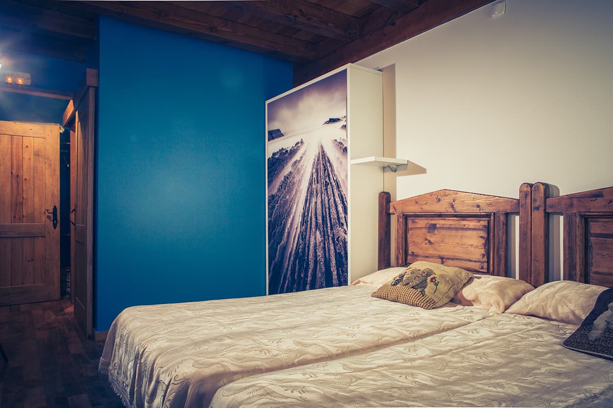 Dormitorio de paredes azules con cama doble y mural