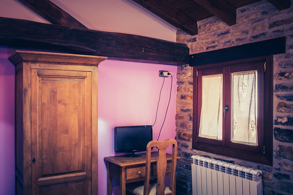 Habitación con armario de madera, escritorio y televisión