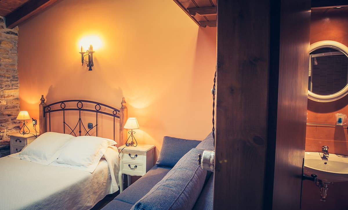 Habitación con dos camas y lavabo con espejo bajo la viga de madera