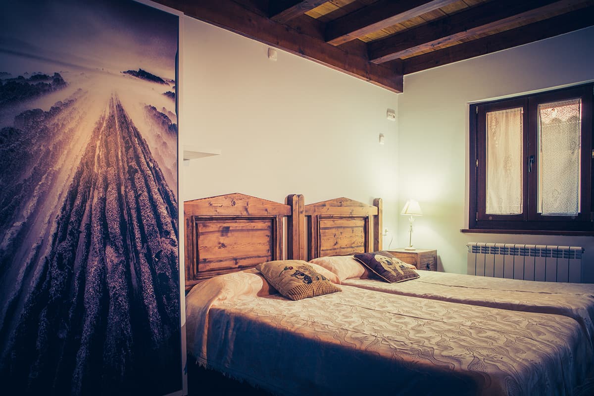 Habitación con cama de madera y un mural de un camino de tablas en la pared