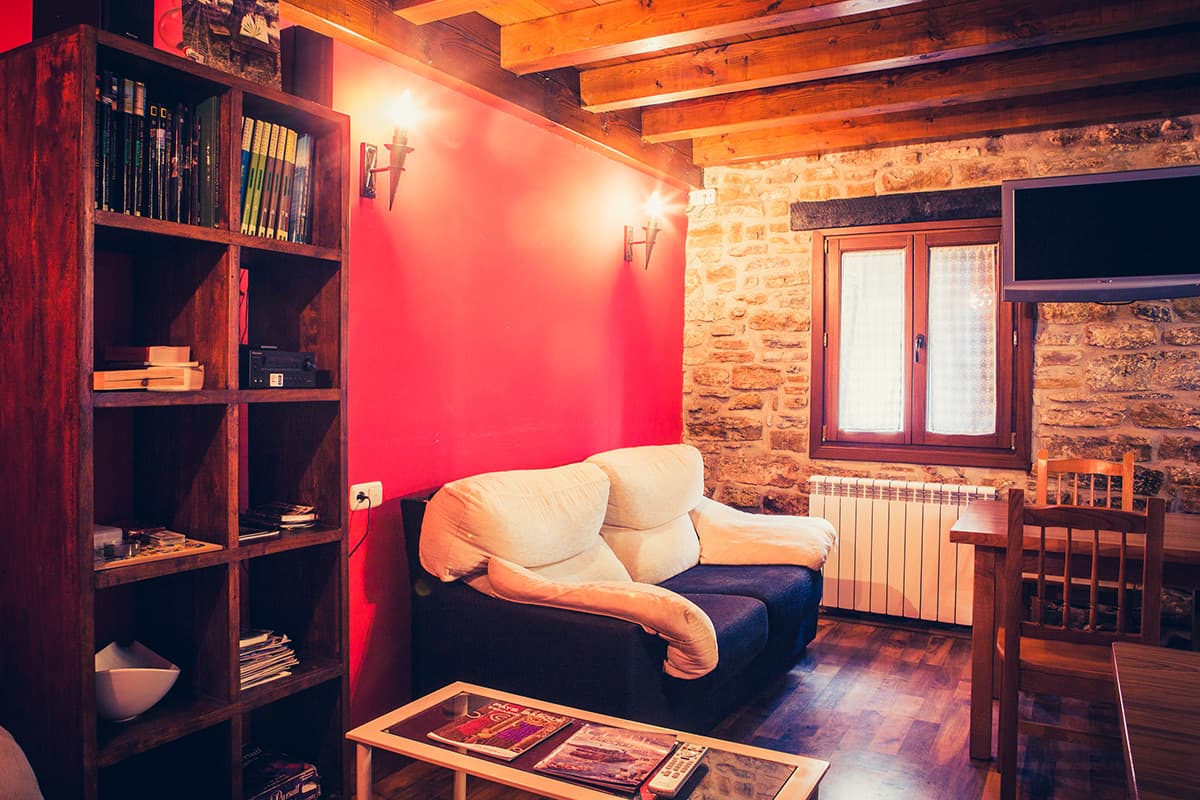 Sala de estar con estantería de libros, sofá y pared roja