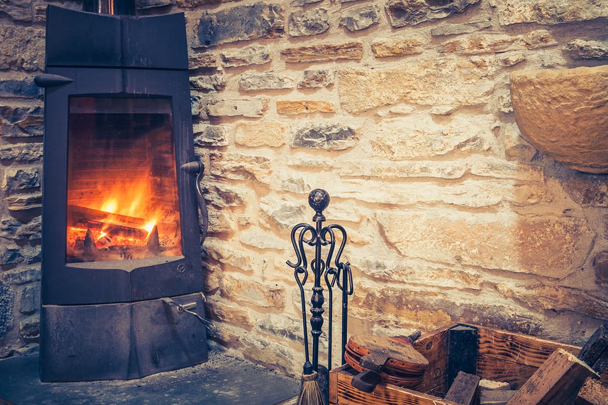 Chimenea encendida en el muro de piedra de la sala