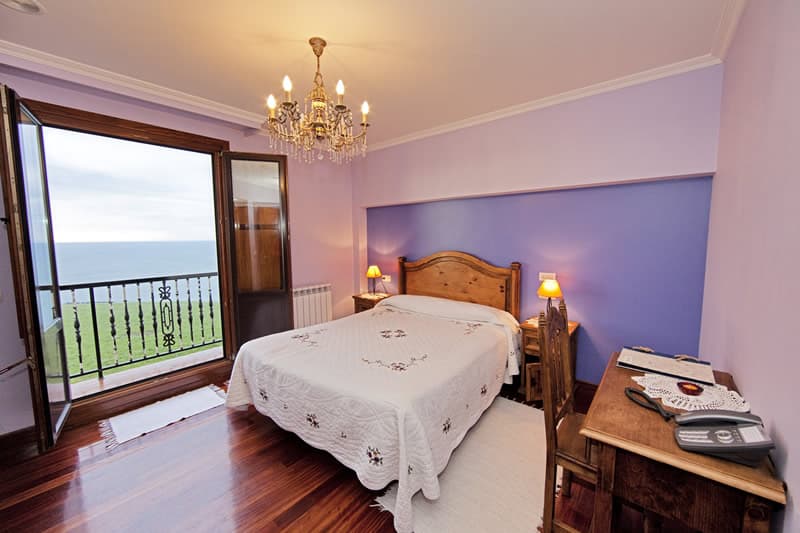 Habitación del agroturismo con ventana abierta sobre los prados y la costa