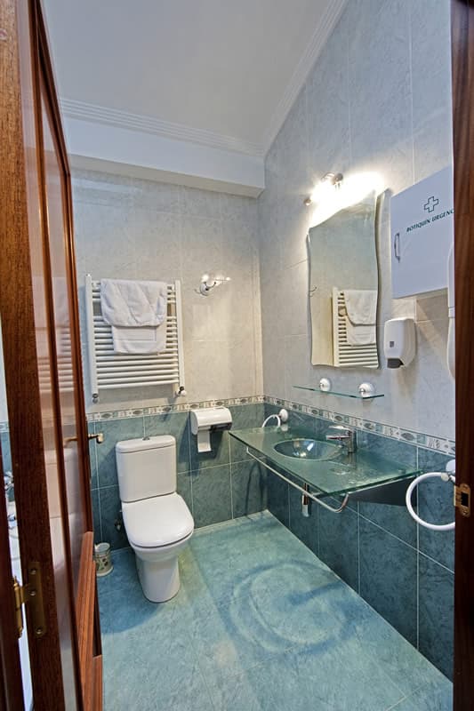 Baño completo del apartamento, alicatado en verde y con toallas preparadas